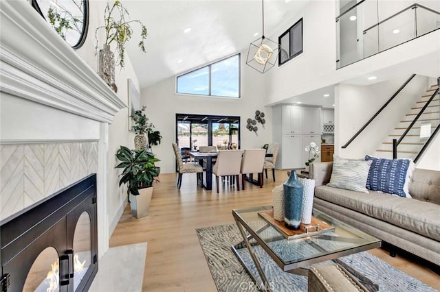 living room with stairs, a high ceiling, and light wood-type flooring