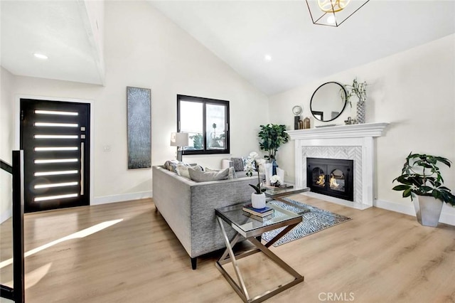 living room featuring high vaulted ceiling, baseboards, wood finished floors, and a tile fireplace