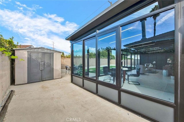 exterior space featuring a sunroom, fence, a storage unit, an outdoor structure, and a patio area