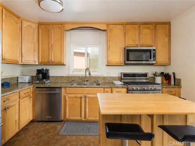 kitchen featuring sink, dark tile patterned flooring, ornamental molding, light stone counters, and stainless steel appliances