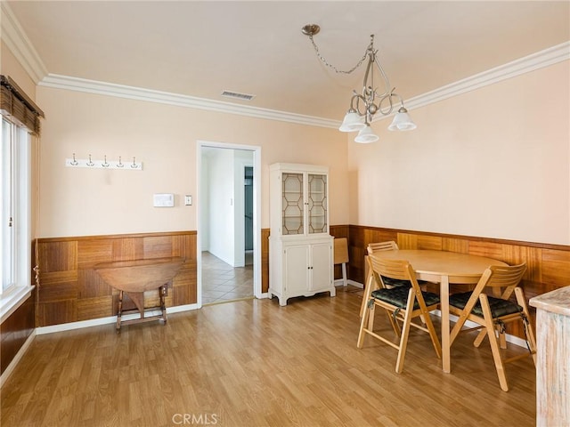 dining space featuring ornamental molding, wood-type flooring, and a chandelier