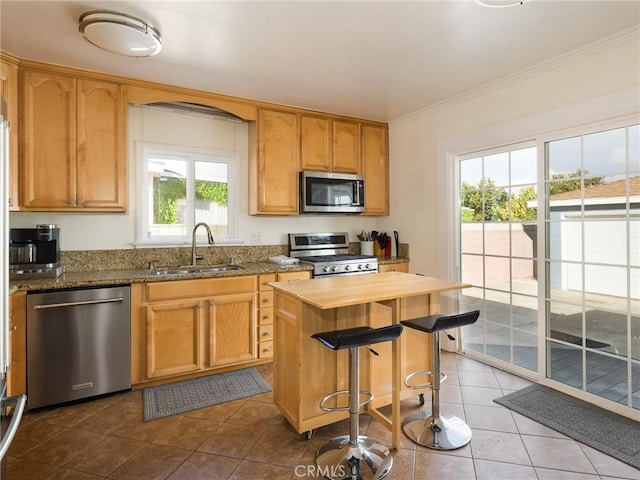 kitchen with sink, crown molding, appliances with stainless steel finishes, a center island, and light stone countertops