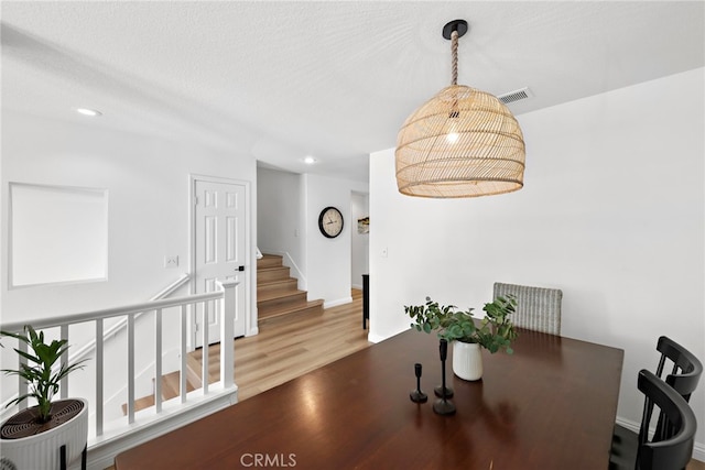 dining space featuring wood-type flooring and a textured ceiling