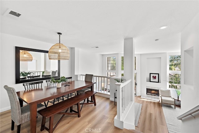 dining area with a tile fireplace, plenty of natural light, and light wood finished floors