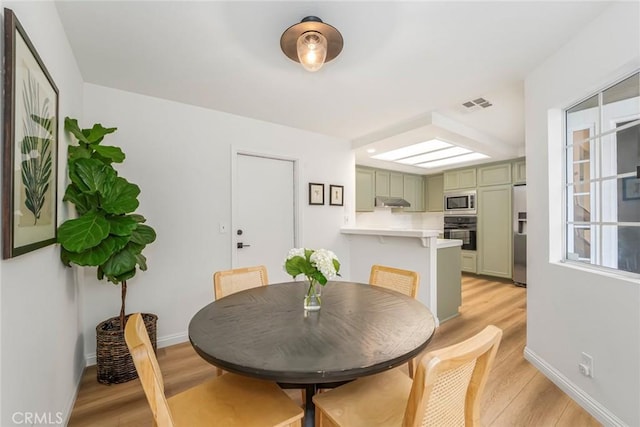 dining space featuring baseboards, visible vents, and light wood-style floors