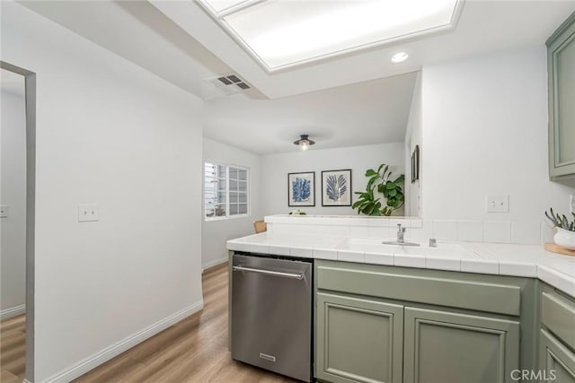 kitchen with visible vents, light wood-style flooring, a sink, dishwasher, and a peninsula