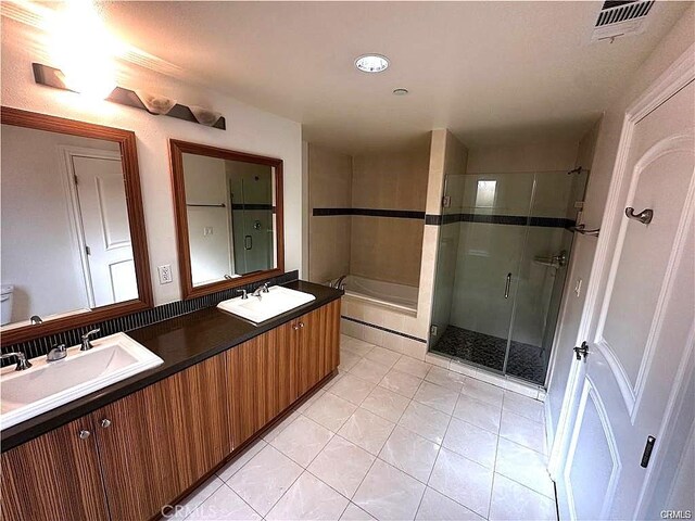 bathroom with a shower with door, vanity, and tile patterned floors