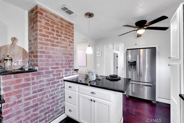 kitchen with pendant lighting, dark hardwood / wood-style flooring, stainless steel fridge, and white cabinets