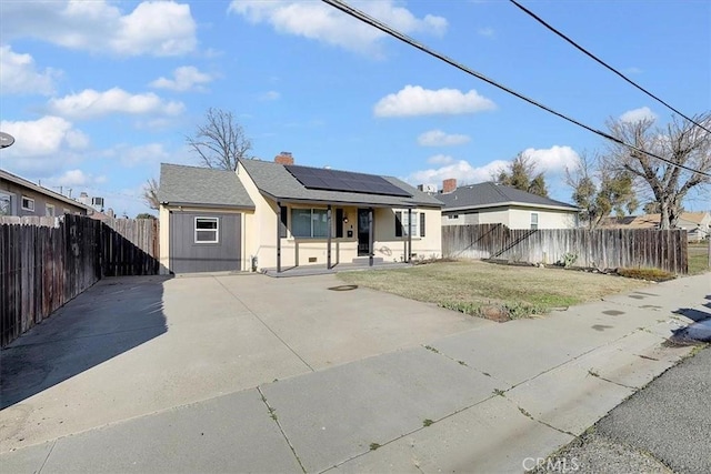 view of front facade featuring covered porch, a front yard, and solar panels