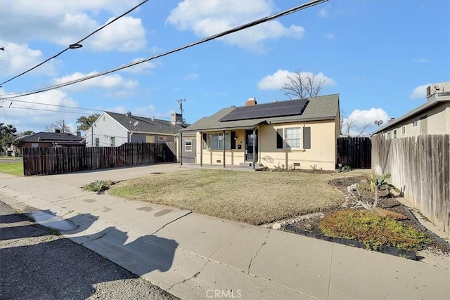 bungalow-style home featuring a front yard, covered porch, and solar panels