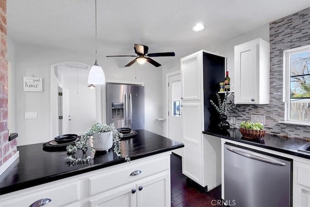 kitchen featuring appliances with stainless steel finishes, dark hardwood / wood-style floors, tasteful backsplash, white cabinets, and hanging light fixtures