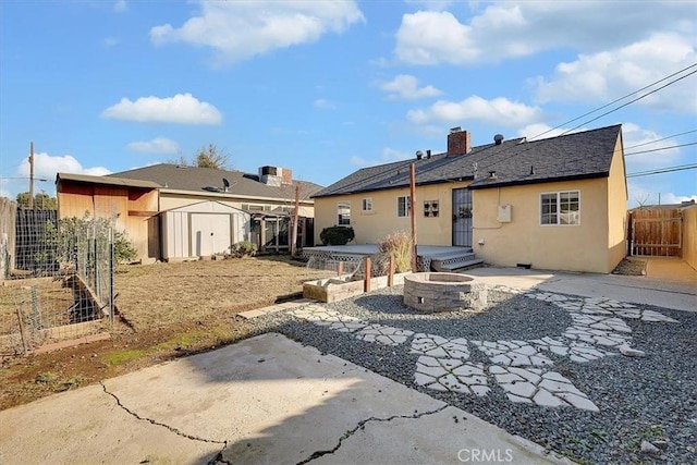 rear view of property with an outdoor fire pit, a shed, and a patio area