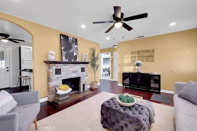 living room with ceiling fan, dark hardwood / wood-style floors, and a fireplace