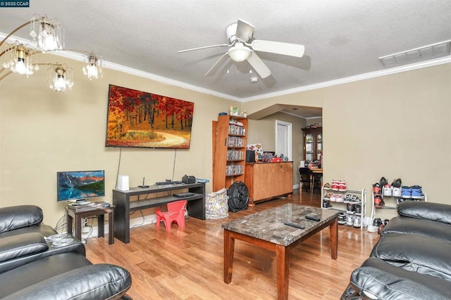 living room featuring hardwood / wood-style flooring, crown molding, ceiling fan with notable chandelier, and a textured ceiling