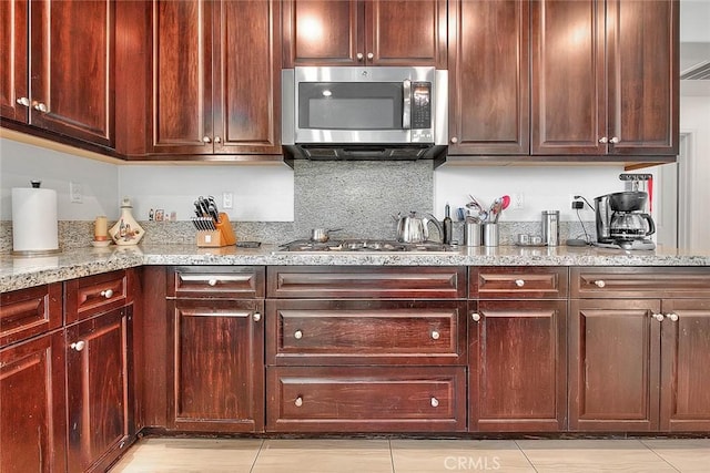 kitchen featuring stainless steel appliances, light stone counters, and decorative backsplash