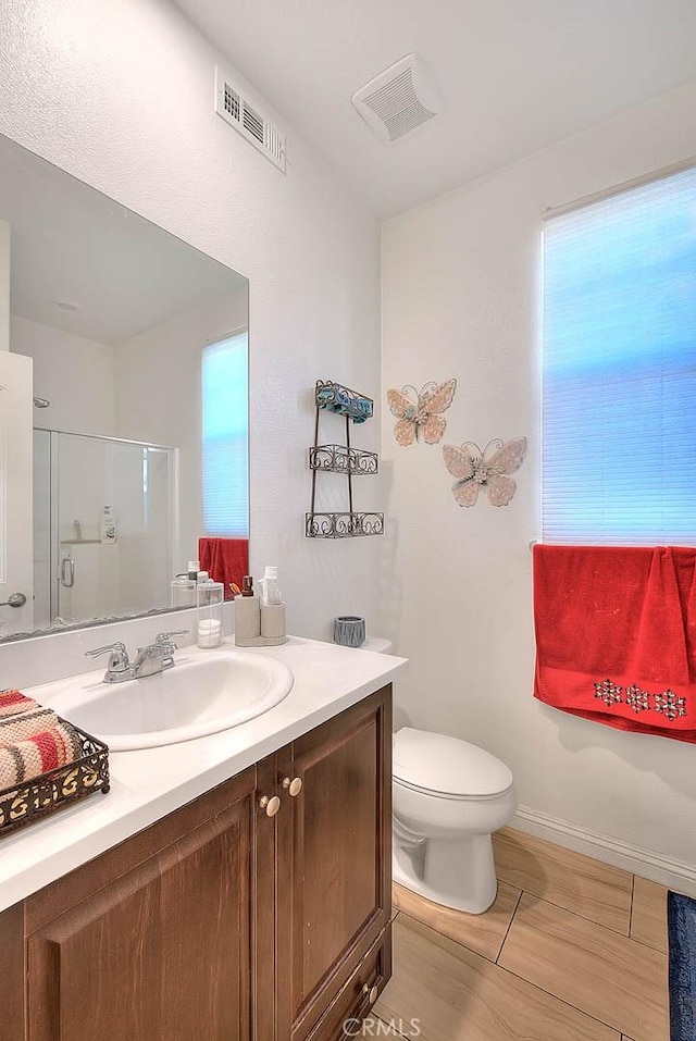 bathroom featuring a shower with door, vanity, hardwood / wood-style flooring, and toilet