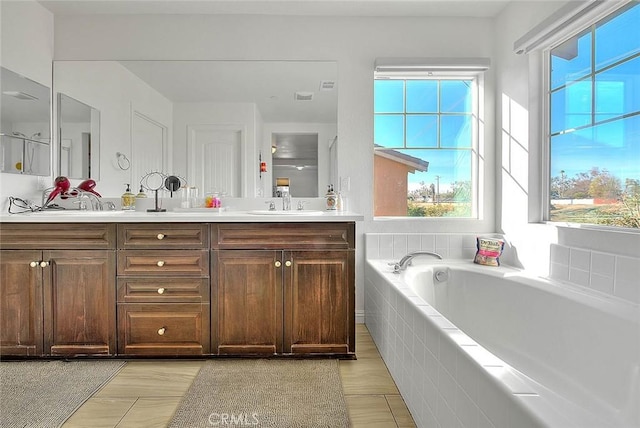 bathroom with vanity and tiled tub