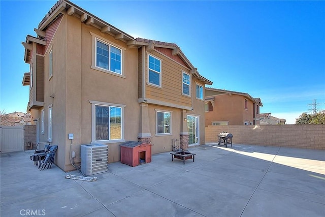 back of house with a patio area, central air condition unit, and a fire pit