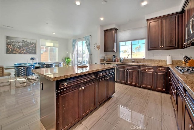 kitchen featuring sink, dark brown cabinets, a healthy amount of sunlight, and a kitchen island