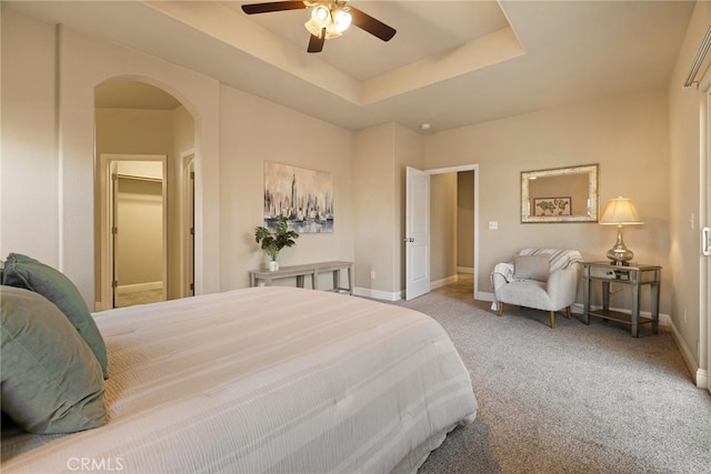 bedroom featuring light colored carpet, a raised ceiling, and ceiling fan