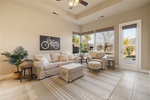 living room featuring light tile patterned floors, a tray ceiling, a wealth of natural light, and ceiling fan