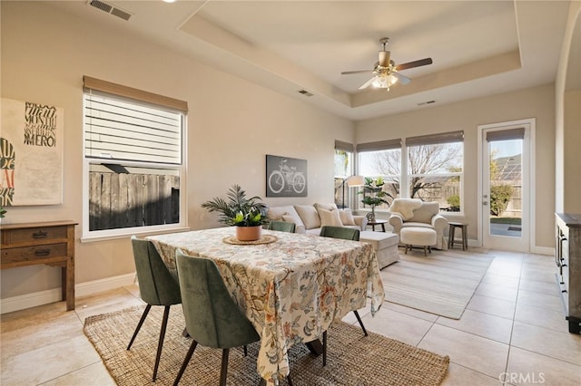 tiled dining area with a raised ceiling and ceiling fan