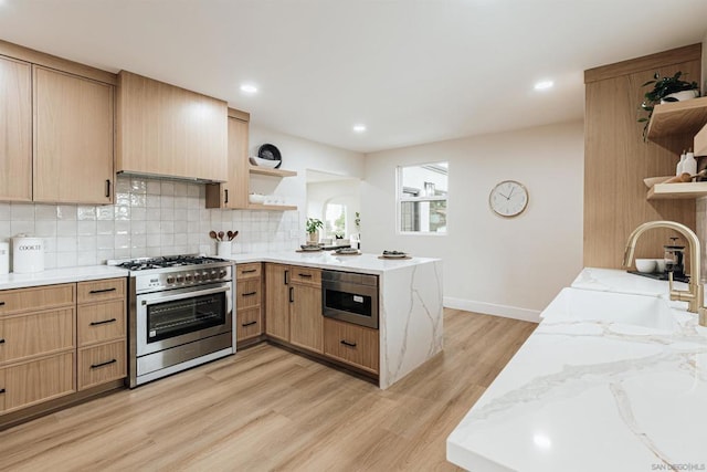 kitchen featuring built in microwave, light stone counters, light wood-type flooring, stainless steel range, and kitchen peninsula