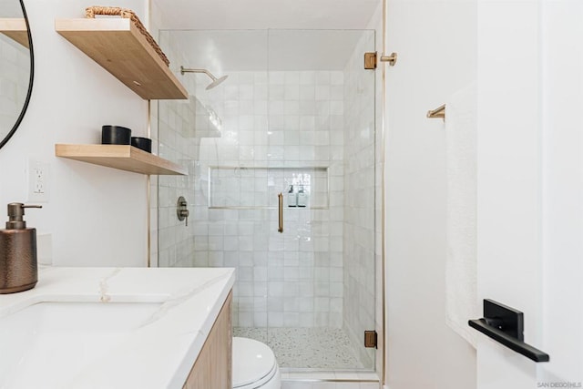 bathroom featuring vanity, toilet, and a shower with door