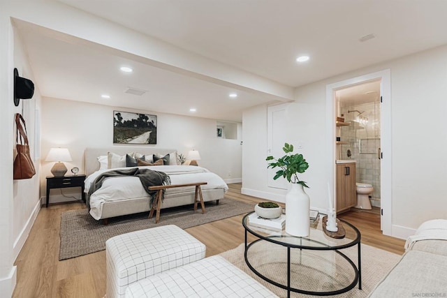 bedroom featuring connected bathroom and light hardwood / wood-style floors