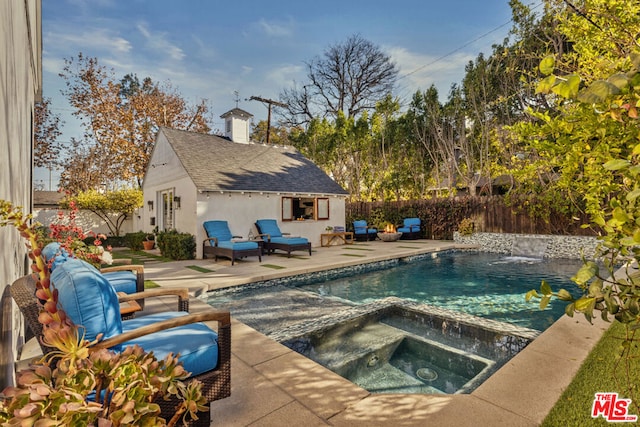 view of swimming pool with an in ground hot tub, an outbuilding, and a patio