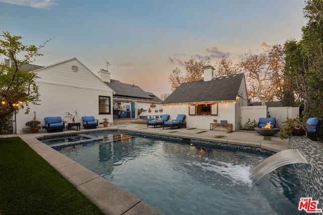 pool at dusk with outdoor lounge area and a patio area