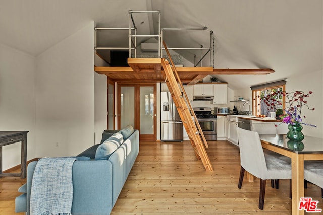 living room featuring sink, vaulted ceiling, and light wood-type flooring