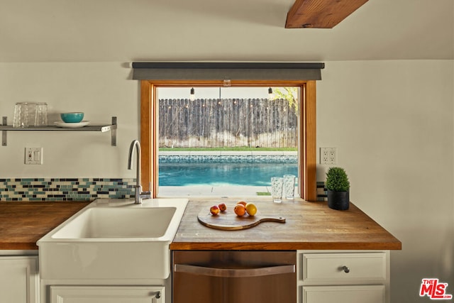 kitchen featuring white cabinetry, butcher block counters, sink, and backsplash