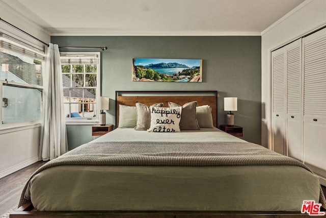 bedroom with hardwood / wood-style flooring, crown molding, and a closet