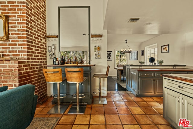 kitchen with a breakfast bar, brick wall, decorative light fixtures, and a chandelier