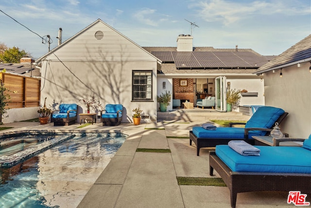 rear view of house featuring outdoor lounge area, a patio area, and solar panels