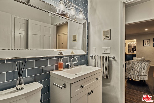 bathroom with hardwood / wood-style flooring, tile walls, backsplash, vanity, and toilet