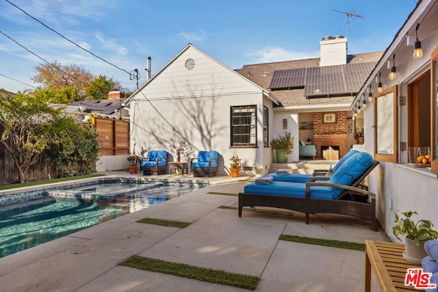 back of house with a fenced in pool, an outdoor hangout area, a patio area, and solar panels