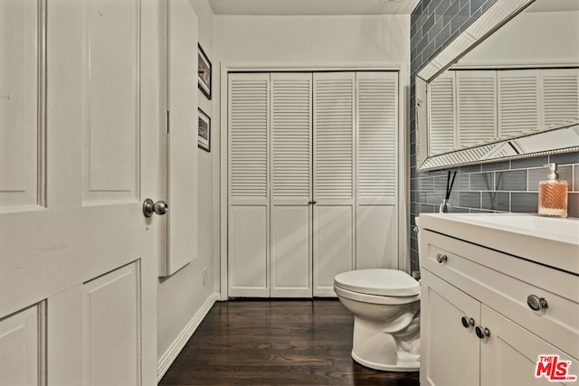 bathroom with hardwood / wood-style flooring, vanity, tile walls, and toilet