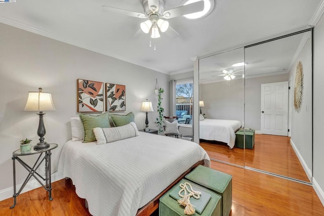 bedroom with crown molding, wood-type flooring, a closet, and ceiling fan