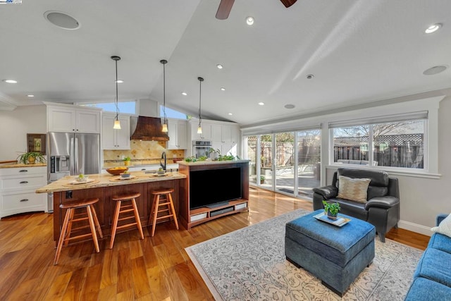 living room with ceiling fan, lofted ceiling, sink, and light hardwood / wood-style floors