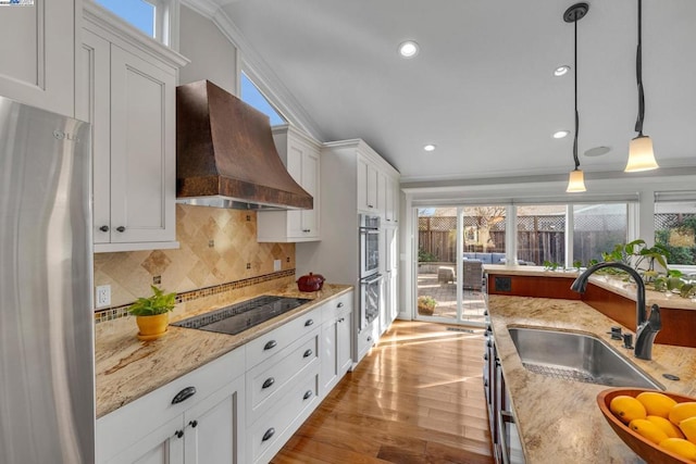 kitchen with sink, premium range hood, hanging light fixtures, stainless steel appliances, and white cabinets