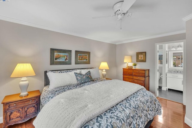 bedroom featuring crown molding, hardwood / wood-style floors, ceiling fan, and ensuite bath