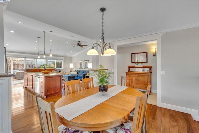 dining area with vaulted ceiling, ornamental molding, sink, and light hardwood / wood-style floors