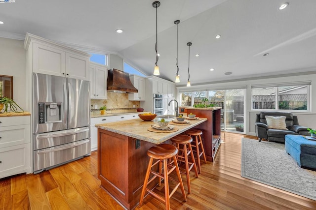 kitchen with white cabinetry, a center island with sink, premium range hood, and appliances with stainless steel finishes