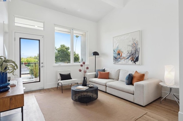 living room featuring vaulted ceiling with beams and light hardwood / wood-style floors