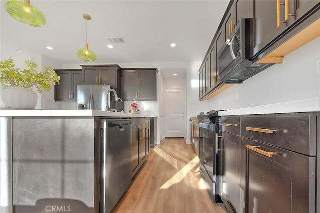 kitchen featuring sink, light hardwood / wood-style flooring, appliances with stainless steel finishes, hanging light fixtures, and dark brown cabinets