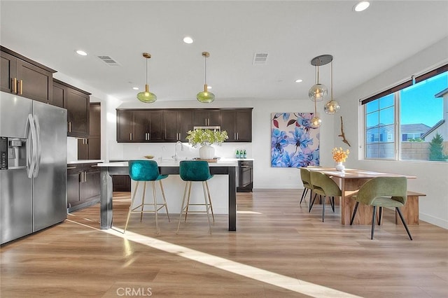 kitchen with a center island, stainless steel fridge, decorative light fixtures, and dark brown cabinets