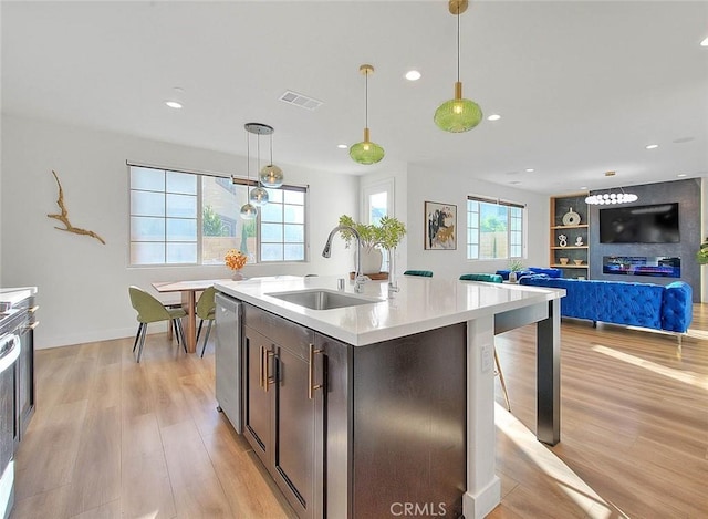 kitchen featuring a center island with sink, dishwasher, sink, and pendant lighting