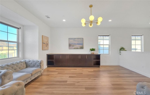 living room featuring an inviting chandelier, light hardwood / wood-style floors, and a healthy amount of sunlight